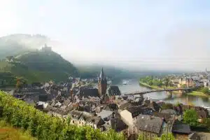 Bernkastel-Kues aan de Moezel. Uitzicht op de twee delen van de stad waar de Moezel tussen stroomt met groene, glooiende wijnheuvels op de achtergrond.