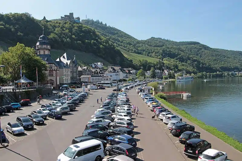 parkeren in Bernkastel-Kues. een grote parkeerplaats met auto's aan de oever van de moezel met de groene heuvels en de stad op de achtergrond